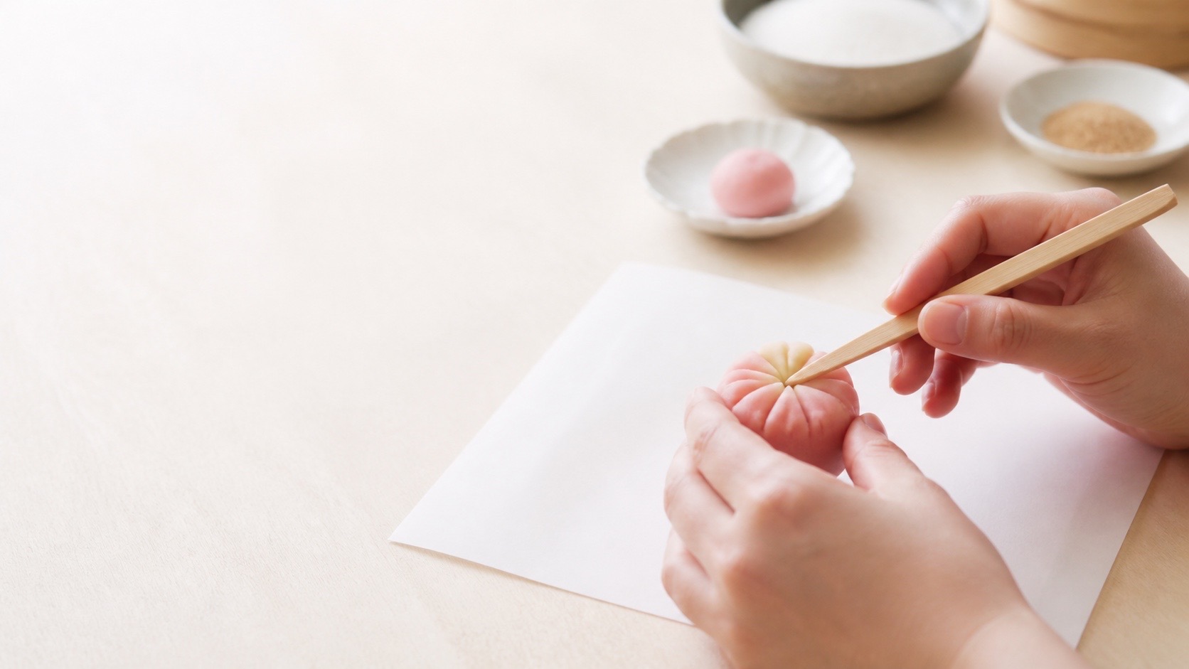 Anonymous hands shaping a seasonal wagashi with a wooden tool